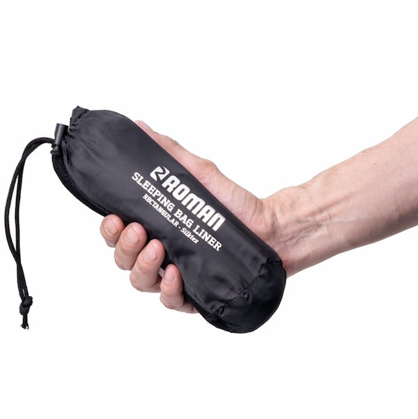 Hand holding a black sleeping bag liner with 'Roman' branding on a white background