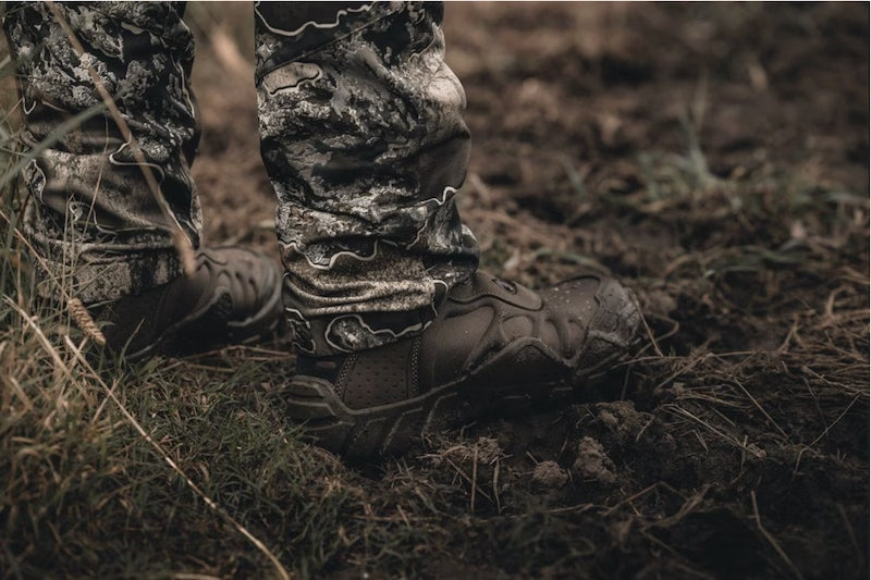 Camouflage pants and boots on a person standing in a natural setting