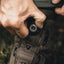 Close-up of a person adjusting the laces on a brown hiking boot with a blurred natural background.