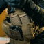 Person wearing a tactical vest with multiple pouches and gear.