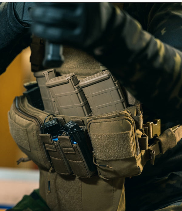 Person wearing a tactical vest with multiple pouches and gear.
