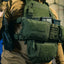 Person wearing a tactical vest with various pouches and equipment.
