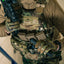 Person in military gear holding a rifle with a neutral background