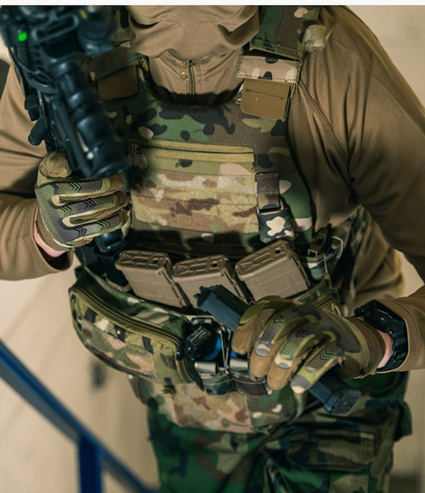 Person in military gear holding a rifle with a neutral background