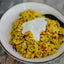 Yellow rice dish with a dollop of white sauce in a white bowl.