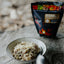 Mushroom and wild herb risotto in a bowl with a package of risotto in the background on a wooden surface.