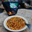 Bowl of food on a stone surface with a backpack in the background