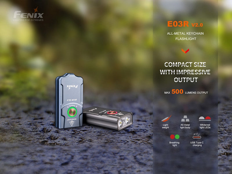 Fenix E03R v2.0 keychain flashlight on a textured surface with blurred natural background