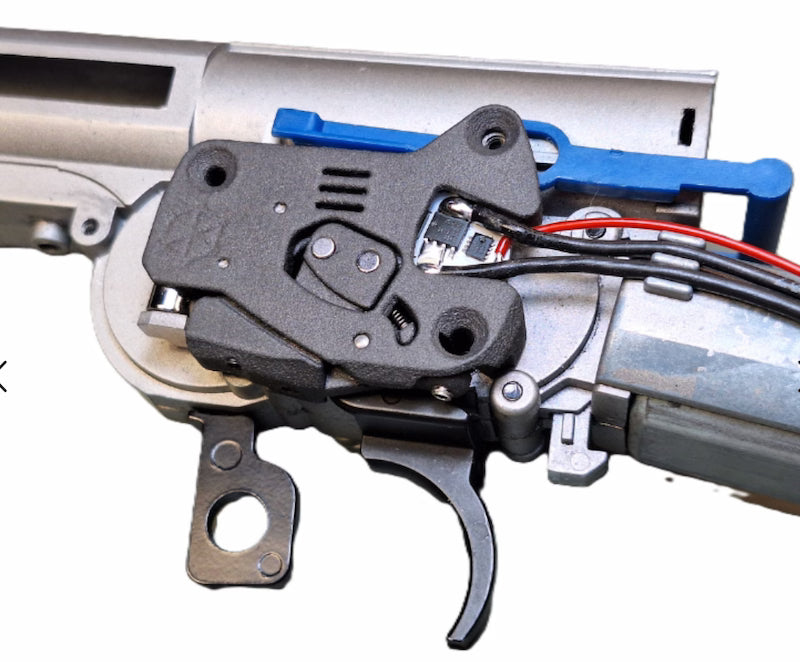 Close-up of a gun's trigger mechanism with visible wiring on a white background