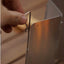 Hand adjusting a metal hook on a reflective surface