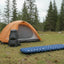 Orange tent, backpack, and blue sleeping pad in a forest setting