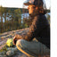 Person in outdoor setting with a lake and trees in the background