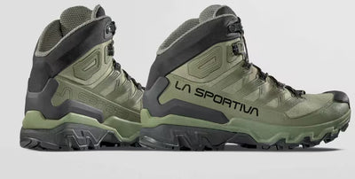 Green hiking boots with black soles on a light gray background, featuring the La Sportiva logo.