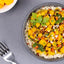 Bowl of rice with yellow vegetable dish on a gray surface