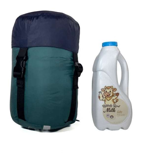 Green and navy backpack next to a white milk jug with a cartoon cow label on a white background
