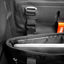 Close-up of a black backpack or duffel bag interior showing a padded compartment, zipper, buckle strap, and a small orange tag with the brand name DAKA.