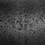 Close-up of a dark textured surface covered with scattered water droplets, shown in black and gray tones.