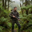 Man with a rifle walking through a dense forest
