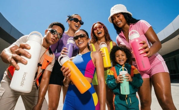 Group of people holding colorful water bottles with a clear blue sky in the background