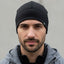 Man wearing a black beanie and gray jacket against a plain background