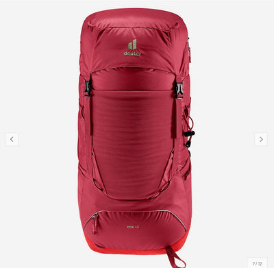 A red Deuter hiking backpack shown from the front on a light gray background, featuring multiple compression straps, side pockets, and a small Deuter logo near the top.
