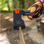 Hand holding a black axe with orange handle in a forest setting