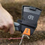 Person using a black and orange tool with a brand logo on a dirt background