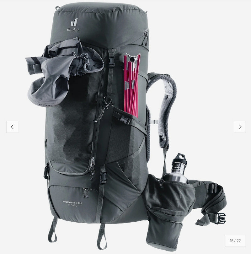 A dark gray Deuter hiking backpack with multiple compartments, shown with a pink trekking pole tucked into a side pocket and a water bottle in a side pouch, on a light gray background.