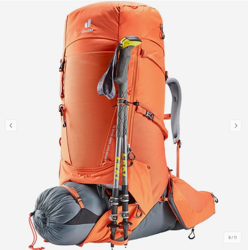 An orange and gray hiking backpack shown on a light gray background, with a gray sleeping bag rolled at the base and two trekking poles leaning against the front. The backpack has the Deerrun brand logo visible near the top left.