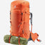 An orange Deuter hiking backpack shown on a light gray background, with a green sleeping bag or gear roll strapped to the bottom and a gray shoulder strap visible on the side.