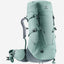 A Deuter hiking backpack in a muted sage green color, shown from a three-quarters front angle against a plain white background.