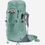 A large hiking backpack in a muted sage green color, shown from a three-quarter angle on a light gray background. The backpack features multiple zippered compartments, a side water bottle pocket holding a silver water bottle, and gray padded shoulder straps.