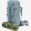 A light gray-blue HUK backpack shown on a white background with an olive green sleeping bag strapped to the bottom.