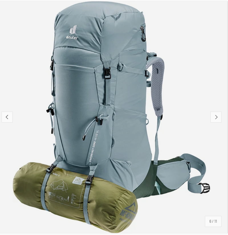 A light gray-blue HUK backpack shown on a white background with an olive green sleeping bag strapped to the bottom.