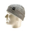A light gray cable-knit beanie with a ribbed cuff and a small black brand patch, displayed on a white mannequin head against a white background.