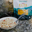 Bowl of food with a fork next to a Back Country Elite package on a rocky surface