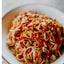 Spaghetti dish with red sauce and meat on a white plate