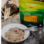 Back Country Cuisine cinnamon rice porridge package with a bowl of porridge and a fork on a stone surface.