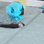 Person applying Seam Grip SIL sealant to a zipper with blue gloves on a gray surface.