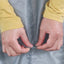 Person adjusting a gray raincoat with yellow sleeves