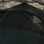 Close-up of a black tent flap with camouflage patterned fabric in the background