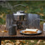 Camping stove with kettle and food on a wooden table outdoors