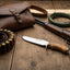 Hunting gear including a rifle, knife, ammunition, and leather bag on a wooden surface.