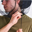 Person wearing a green shirt with a black insect netting over their head against a white background