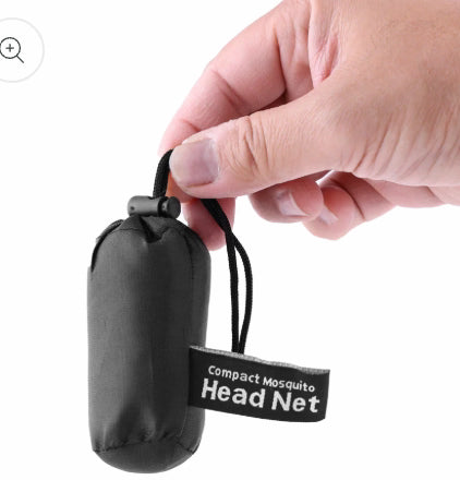 Hand holding a compact mosquito head net with a label on a white background