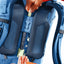 Close-up of a blue backpack with a person adjusting the shoulder strap.