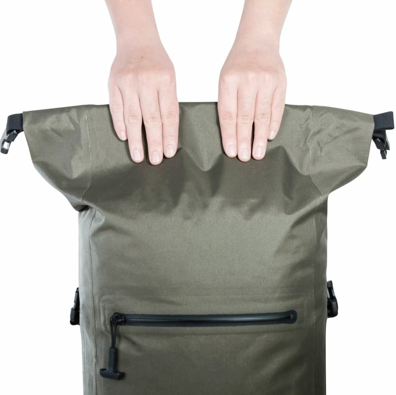 Person holding a green backpack with black zippers on a white background