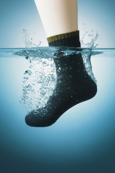 A black sock floating underwater with water splashing around it and a blue gradient background.