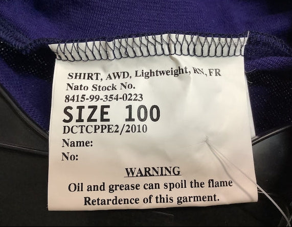A close-up of a white garment size label sewn onto a dark purple shirt, showing text including 'SIZE 100' and a warning about oil and grease.