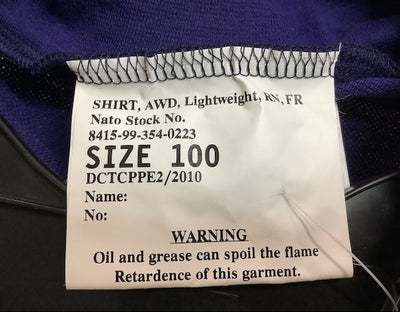 A close-up of a white garment size label sewn onto a dark purple shirt, showing text including 'SIZE 100' and a warning about oil and grease.